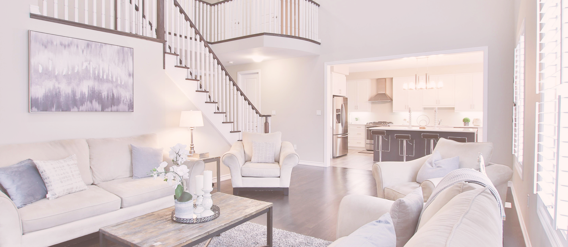 Bright white living room with a high ceiling and dark accents bannisters on stairs by Ottawa construction company
